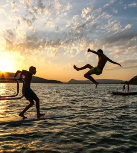 Groupe d'adolescents en train de se baigner dans le lac d'annecy au coucher du soleil