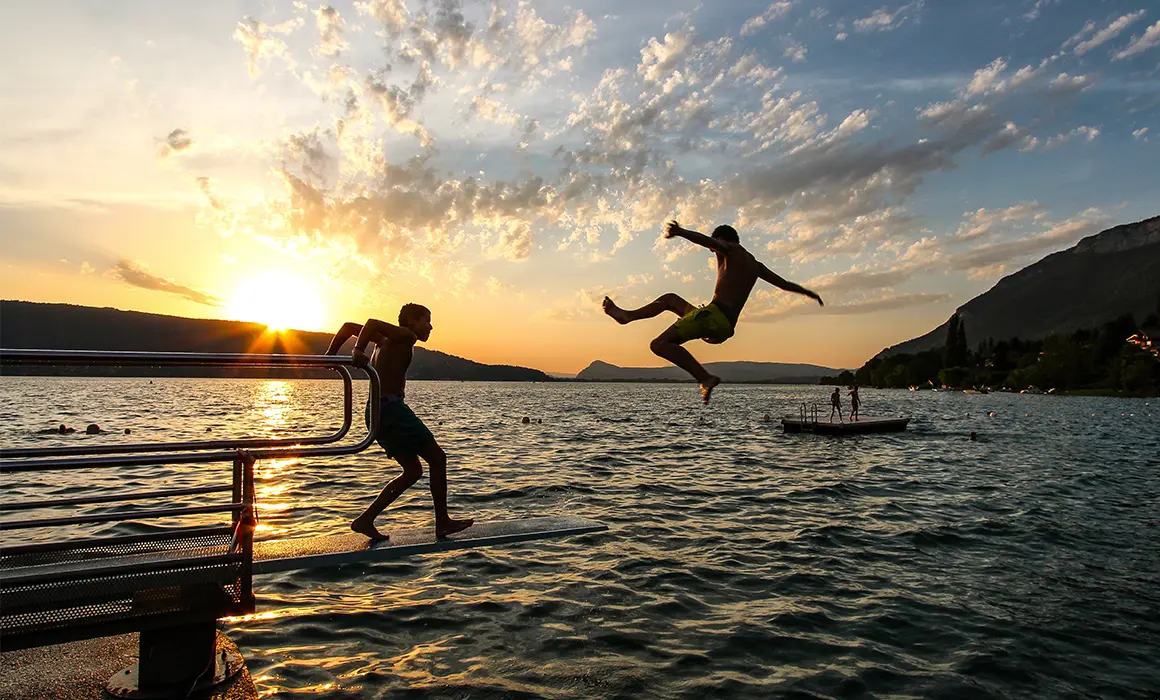 Groupe d'adolescents en train de se baigner dans le lac d'annecy au coucher du soleil